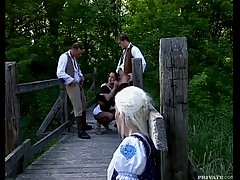 Two naughty sex bombs are down on their knees and sucking a huge fat cock, while outdoors